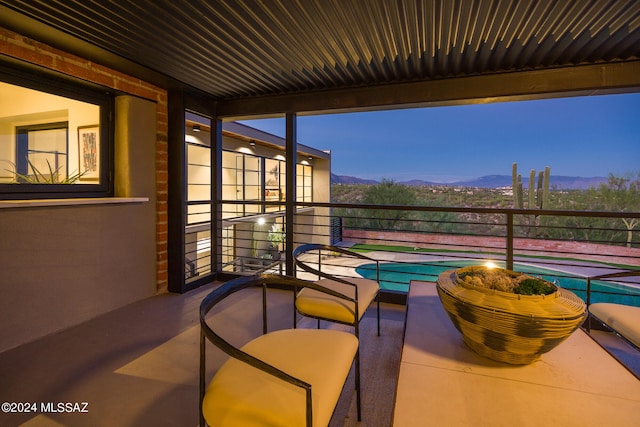 patio terrace at dusk featuring a mountain view and a balcony