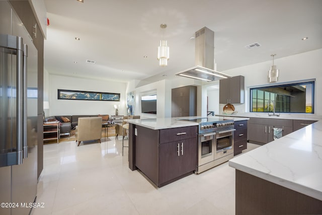 kitchen featuring dark brown cabinets, a large island, island range hood, hanging light fixtures, and high quality appliances