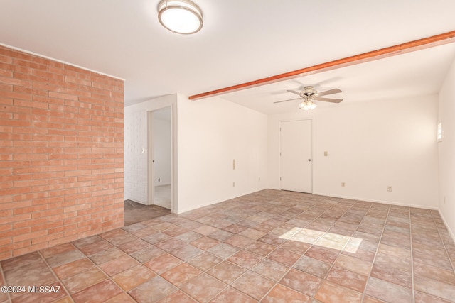 tiled spare room with ceiling fan and brick wall