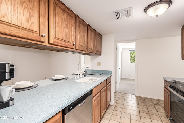 kitchen with appliances with stainless steel finishes, light tile patterned flooring, and sink