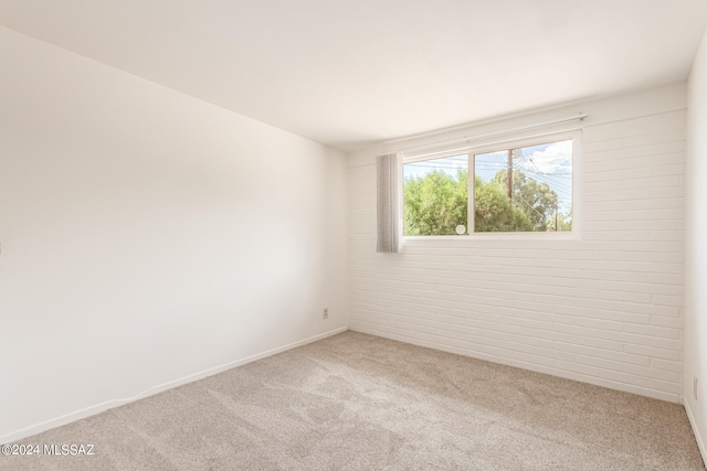 empty room featuring carpet floors and brick wall