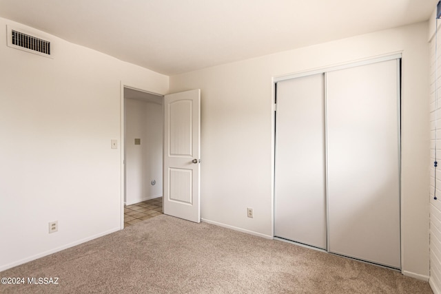 unfurnished bedroom featuring a closet and light colored carpet