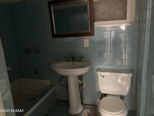 bathroom featuring sink, a shower, toilet, and tile walls