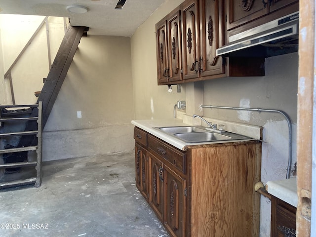 kitchen featuring dark brown cabinets, concrete flooring, and sink