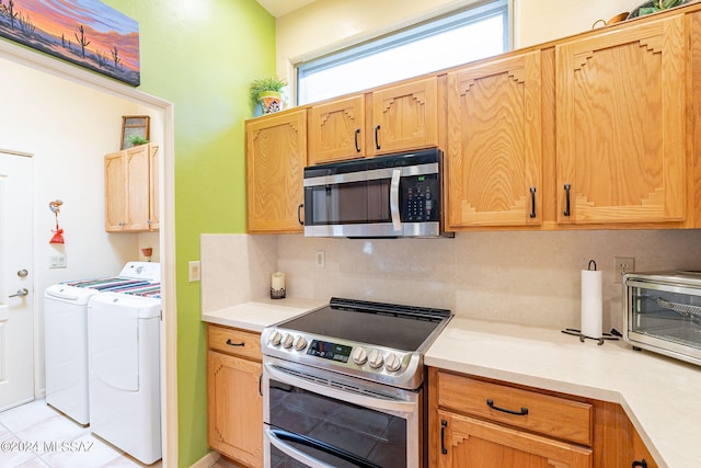 kitchen featuring tasteful backsplash, appliances with stainless steel finishes, light tile patterned flooring, and washing machine and clothes dryer