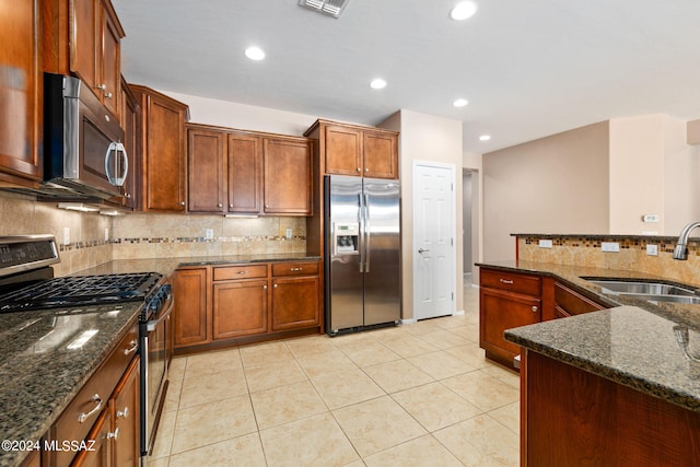 kitchen with dark stone counters, stainless steel appliances, tasteful backsplash, and sink