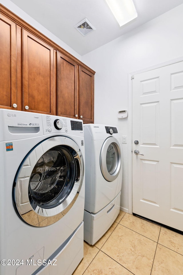 washroom featuring light tile patterned floors, cabinets, and washer and dryer