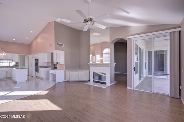 unfurnished living room with light hardwood / wood-style flooring, high vaulted ceiling, and ceiling fan