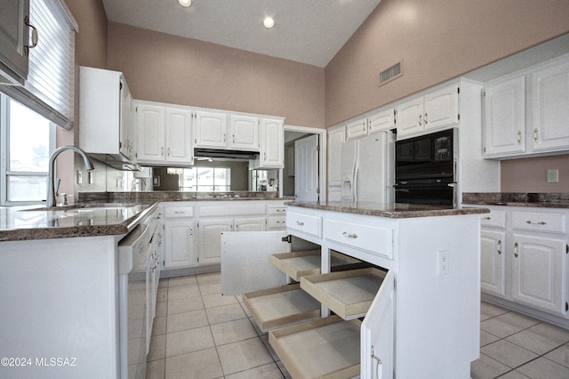 kitchen with white cabinetry, light tile patterned floors, black appliances, and a kitchen island