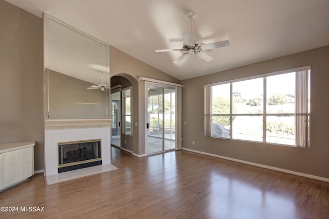 unfurnished living room with ceiling fan, lofted ceiling, wood-type flooring, and a tile fireplace