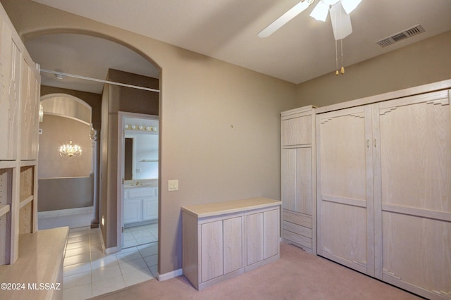 interior space with light tile patterned flooring, ensuite bath, and ceiling fan