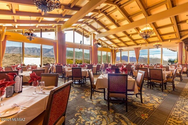 dining room featuring an inviting chandelier, high vaulted ceiling, carpet flooring, a mountain view, and beam ceiling