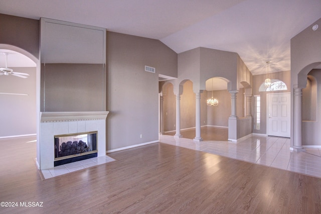 unfurnished living room featuring decorative columns, ceiling fan, a fireplace, and light hardwood / wood-style flooring