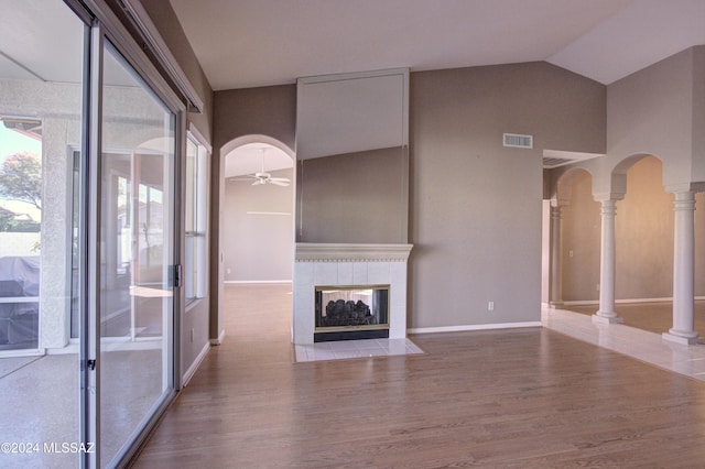 unfurnished living room featuring a tiled fireplace, hardwood / wood-style flooring, decorative columns, and ceiling fan