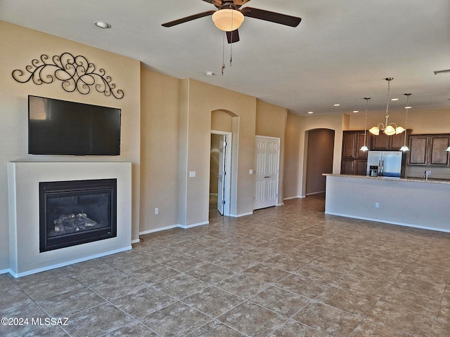 unfurnished living room featuring baseboards, arched walkways, a ceiling fan, a glass covered fireplace, and recessed lighting