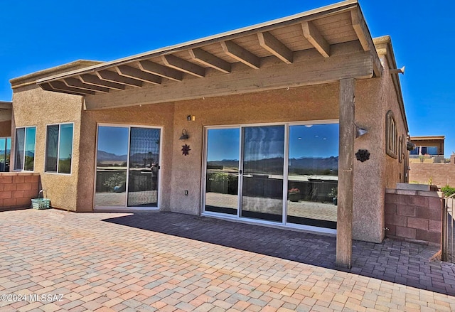 rear view of property with a patio area, fence, and stucco siding