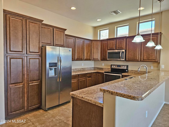 kitchen with light stone counters, stainless steel appliances, a peninsula, a sink, and decorative light fixtures