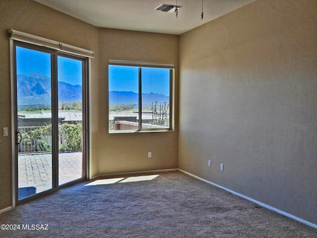 unfurnished room with carpet, visible vents, a mountain view, and baseboards