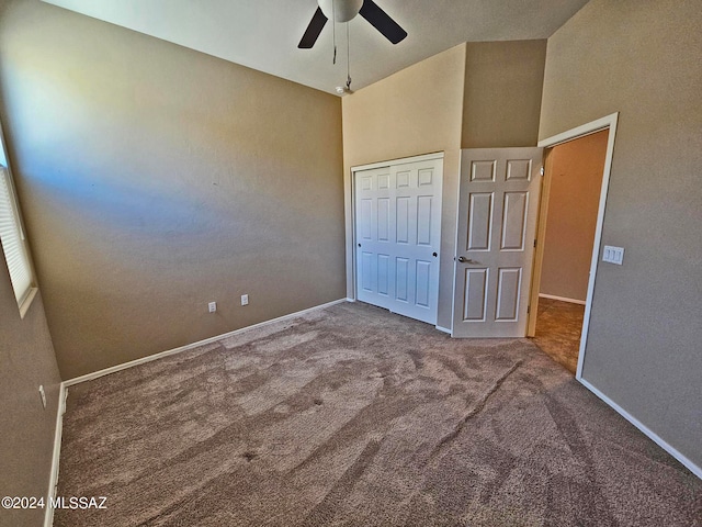 unfurnished bedroom featuring a closet, a ceiling fan, carpet flooring, high vaulted ceiling, and baseboards