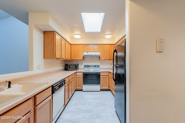 kitchen featuring white appliances, light brown cabinets, sink, and a skylight