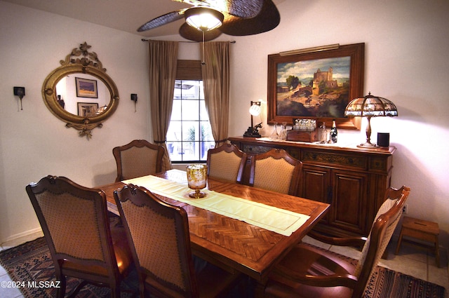 dining space with dark tile patterned floors and ceiling fan