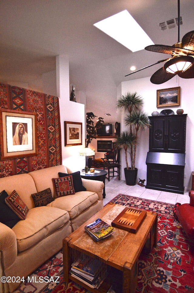 living room with a skylight, light tile patterned flooring, and ceiling fan