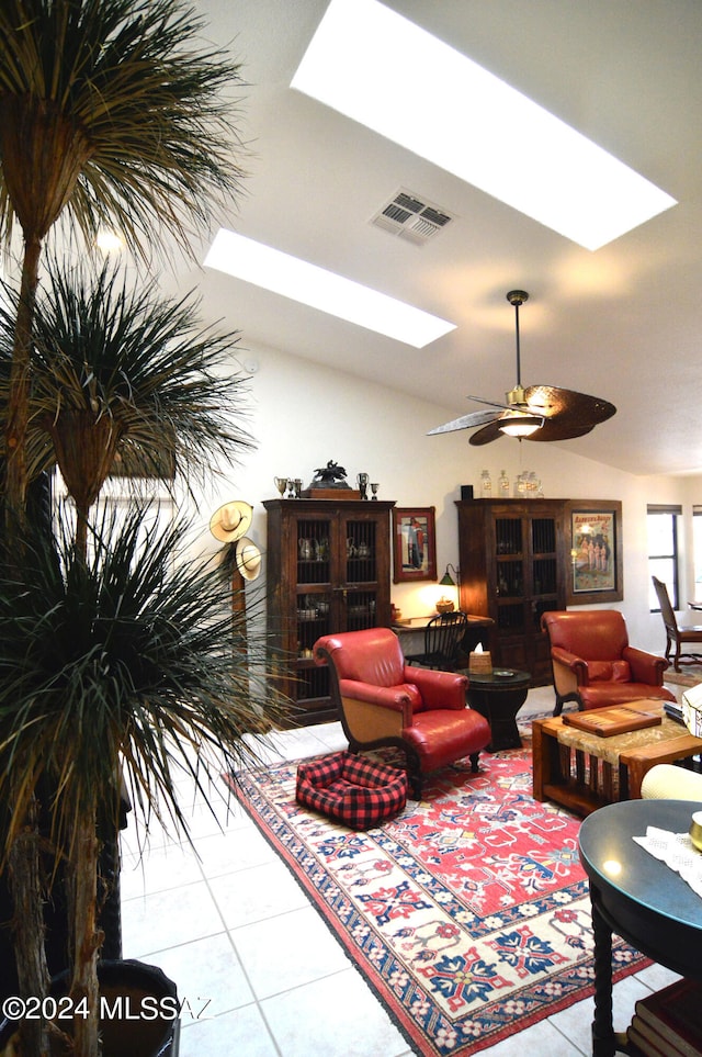 living room with ceiling fan, lofted ceiling, and light tile patterned flooring