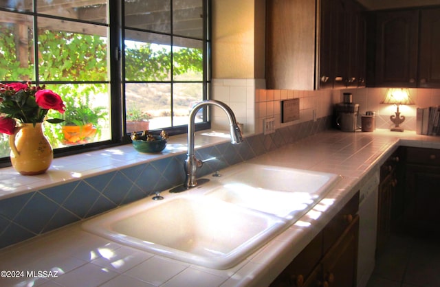 kitchen with tile countertops, dishwasher, sink, and dark brown cabinets