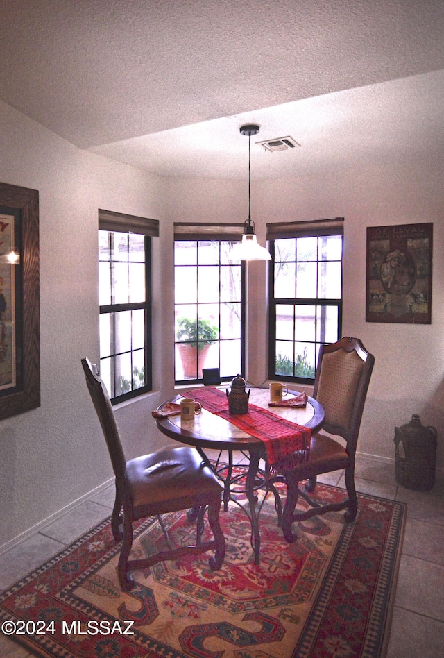 dining area featuring a wealth of natural light, a textured ceiling, and tile patterned flooring