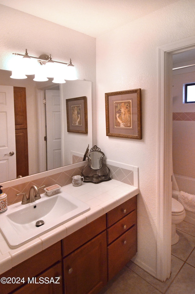 bathroom featuring vanity, a tub to relax in, toilet, and tile patterned floors