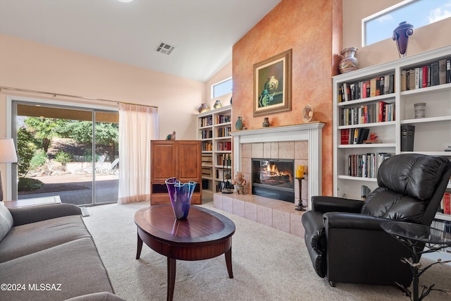 living room with carpet floors, lofted ceiling, plenty of natural light, and a tiled fireplace