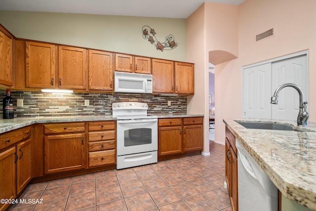 63156 E Flower Ridge Dr, Saddlebrooke, AZ 85739 - kitchen with white appliances, a sink, decorative backsplash, brown cabinetry, and a high ceiling