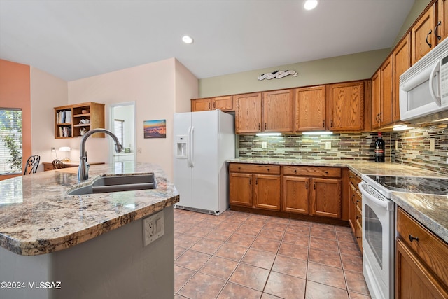 kitchen with an island with sink, light tile patterned flooring, sink, white appliances, and tasteful backsplash