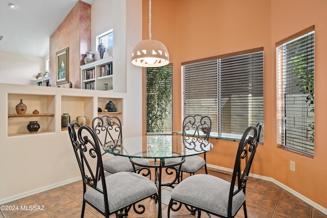 dining room featuring tile patterned flooring, a towering ceiling, and built in shelves