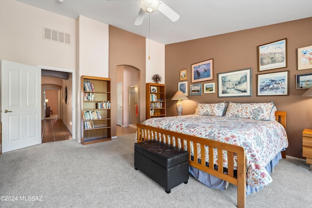 bedroom featuring a towering ceiling, ceiling fan, and carpet flooring