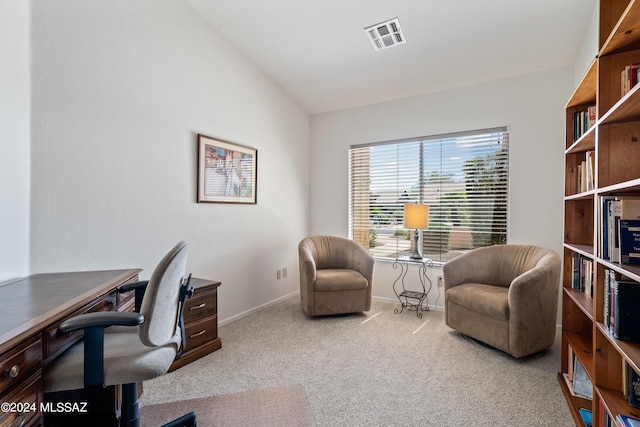 home office with lofted ceiling and light colored carpet