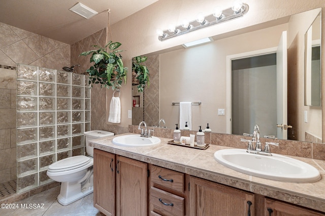 bathroom with vanity, tile patterned floors, toilet, and tiled shower