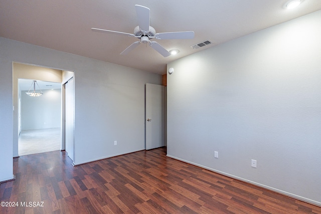 unfurnished room featuring ceiling fan with notable chandelier and dark wood-type flooring