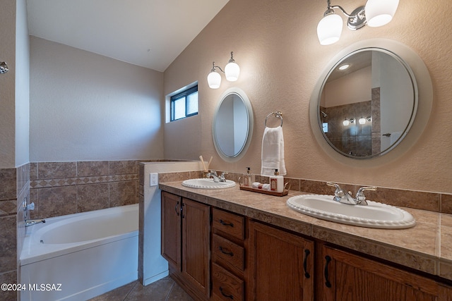 bathroom featuring tile patterned flooring, vaulted ceiling, a bath, and vanity