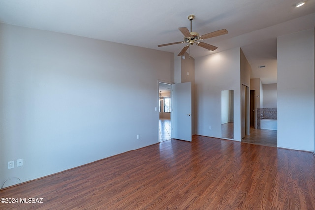 spare room with a towering ceiling, dark wood-type flooring, and ceiling fan