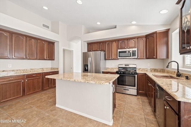 kitchen featuring vaulted ceiling, appliances with stainless steel finishes, sink, and light stone countertops