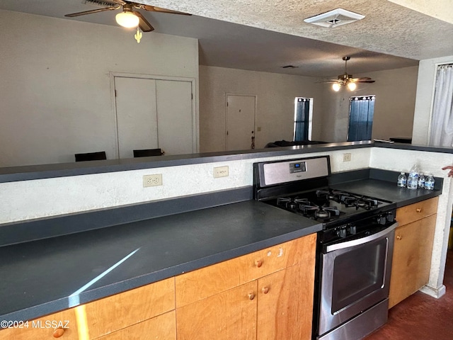 kitchen with a textured ceiling, gas stove, and ceiling fan