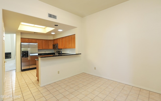 kitchen with stainless steel appliances, kitchen peninsula, a skylight, and light tile patterned floors