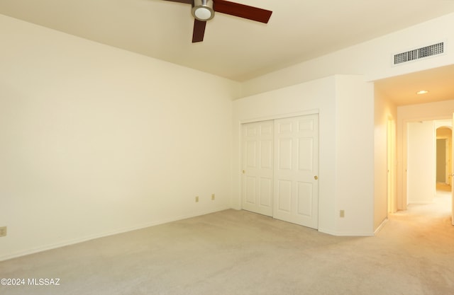 unfurnished bedroom featuring light carpet, a closet, and ceiling fan