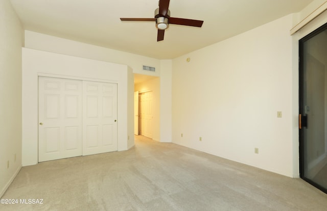 unfurnished bedroom with a closet, light colored carpet, and ceiling fan