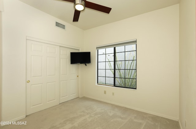 unfurnished bedroom featuring ceiling fan, a closet, and light colored carpet