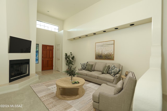 living room with a tiled fireplace and a high ceiling