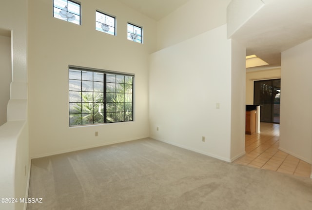 empty room with light carpet, a high ceiling, and a healthy amount of sunlight