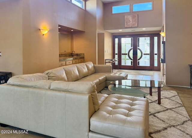 living room featuring french doors, a high ceiling, carpet flooring, and sink