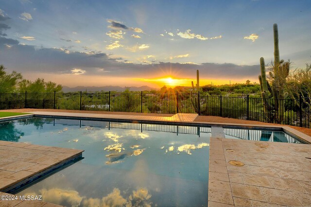 back of property with a yard, a mountain view, a balcony, a swimming pool with hot tub, and a patio area